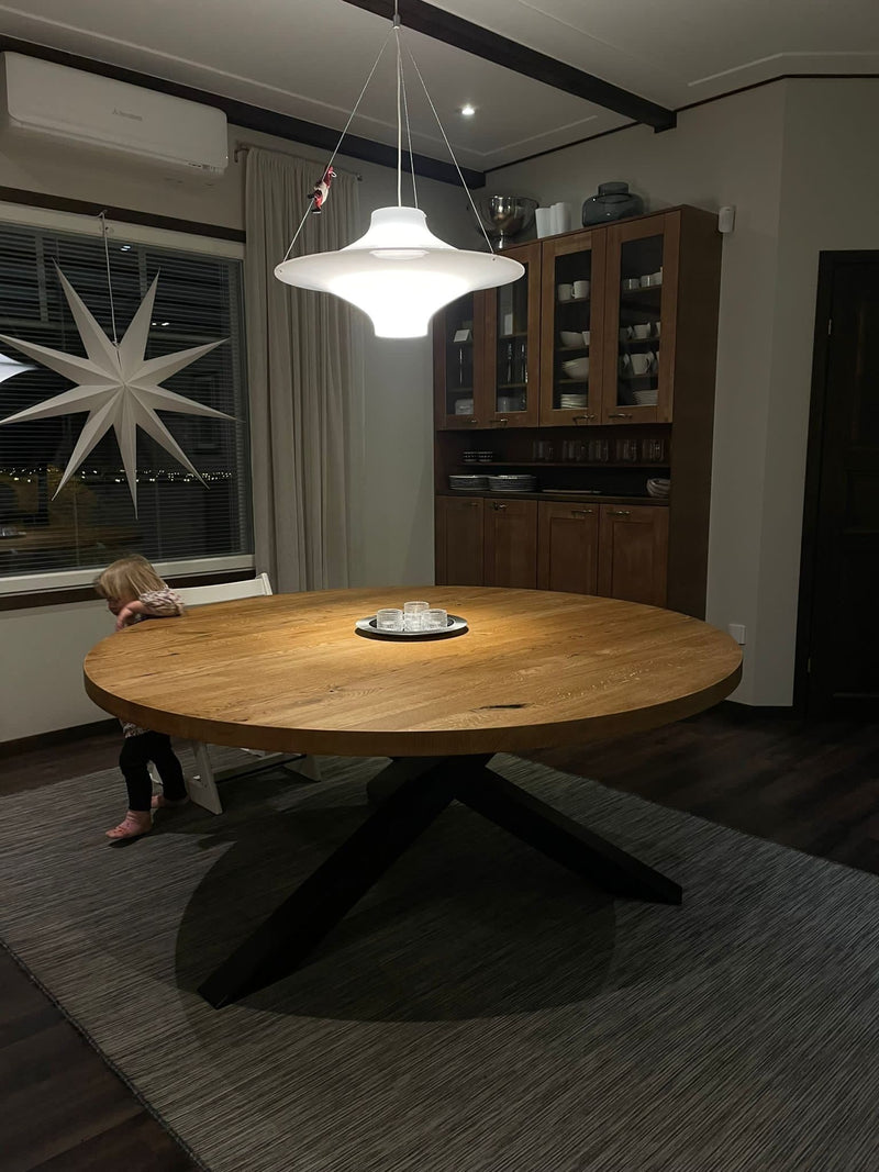 Round wooden dining table in natural oak finish with geometric X-shaped steel legs, Scandinavian-style design