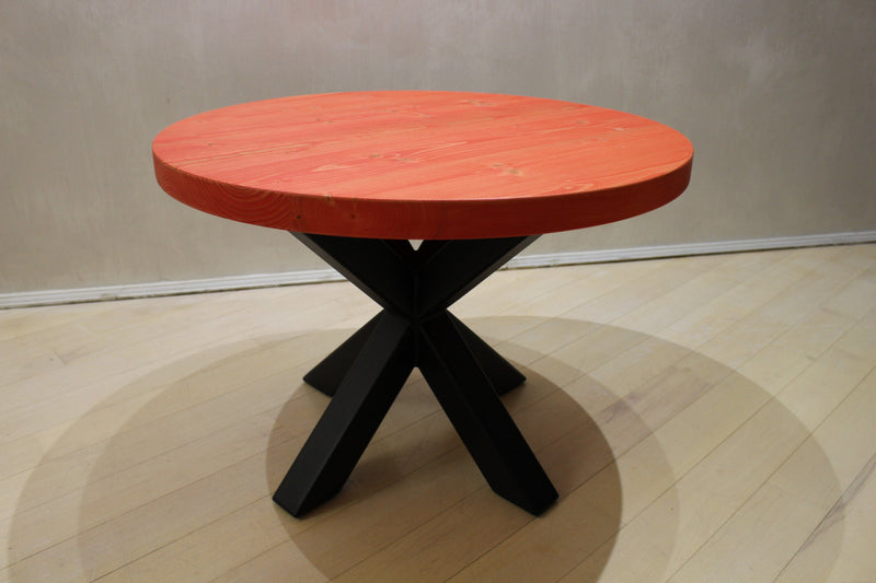Red solid wood coffee table with round top and bold black spider legs, ideal for living rooms and lounges