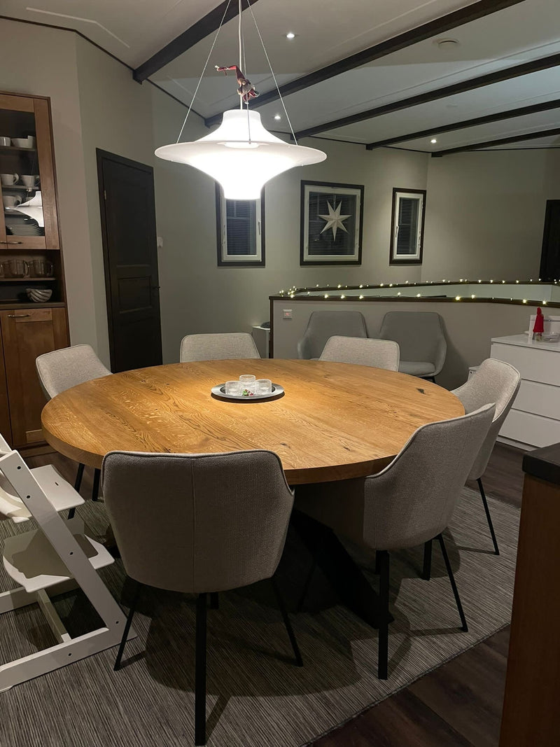 Round solid oak dining table with sculptural X-shaped metal legs, ideal for modern and industrial interiors