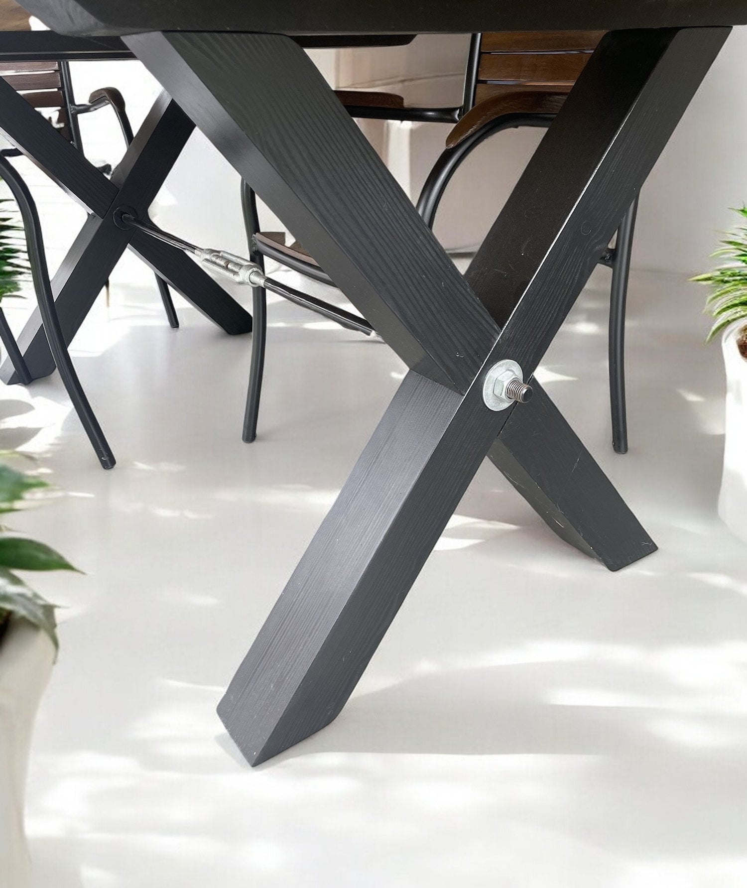 X-shaped black metal table legs with visible bolt and crossbar support, industrial style detail 