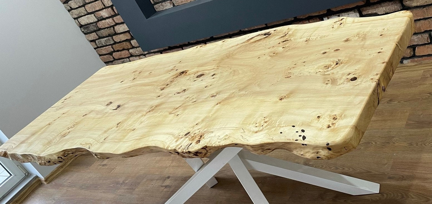 One-piece oak slab dining table with natural edge and powder-coated white steel base