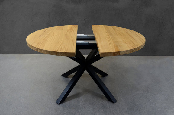 Expandable round oak dining table with black industrial metal legs, perfect for modern loft-style interiors
