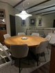 Round solid oak dining table with sculptural X-shaped metal legs, ideal for modern and industrial interiors